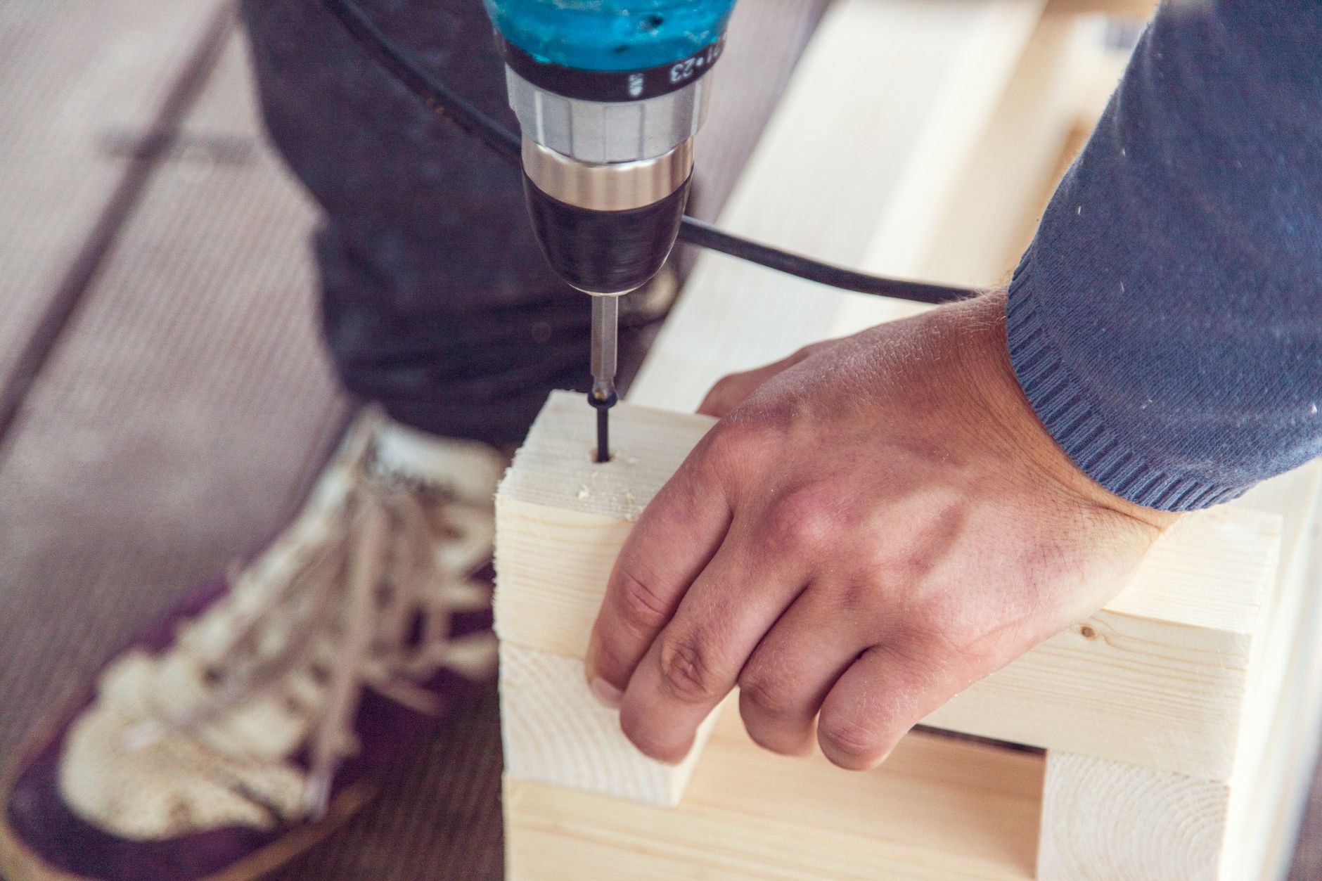 Woodworker drilling a hole in a wooden detail during a home repair project