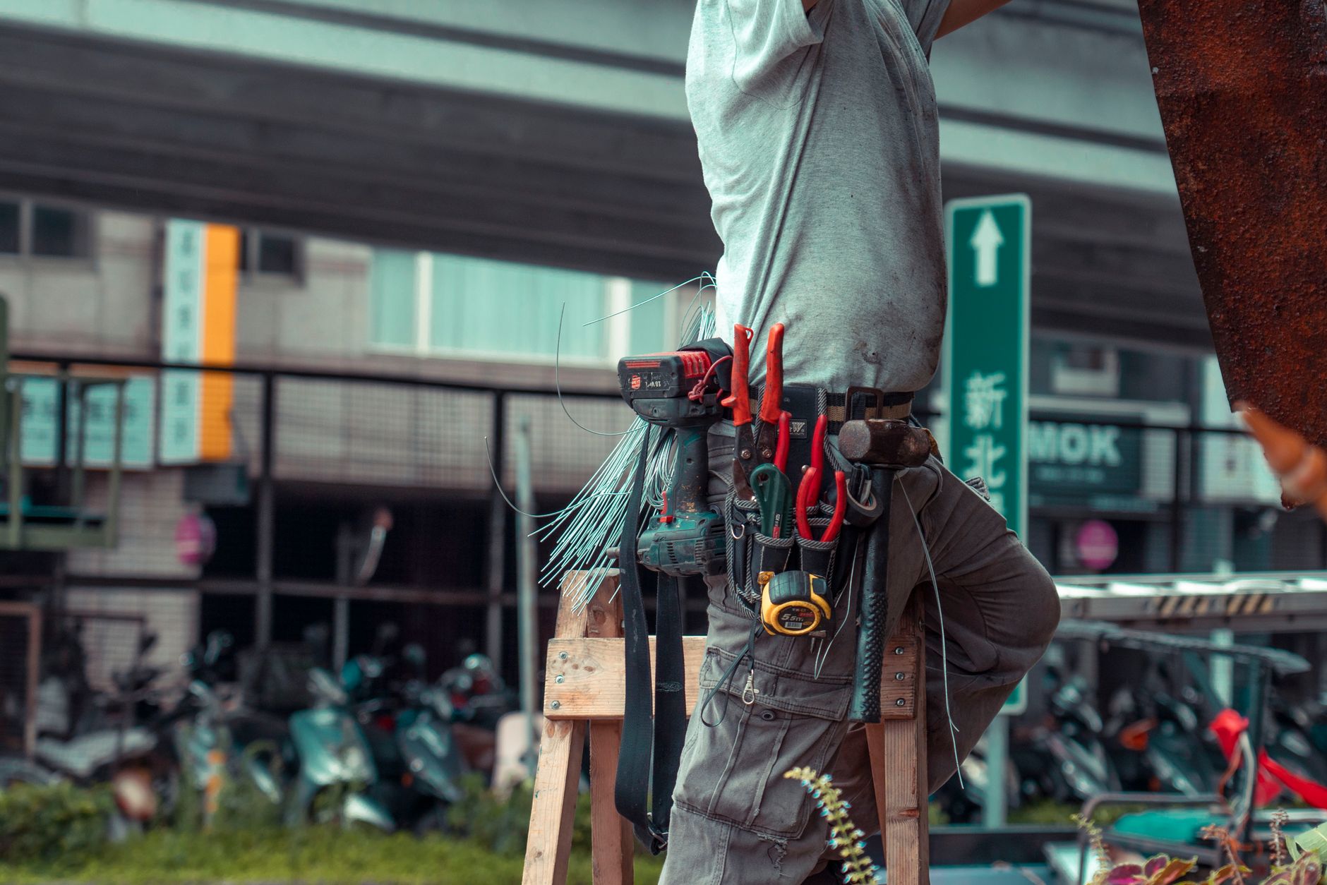Handyman standing on a ladder with a tool belt, making an outdoor repair in Port St Lucie