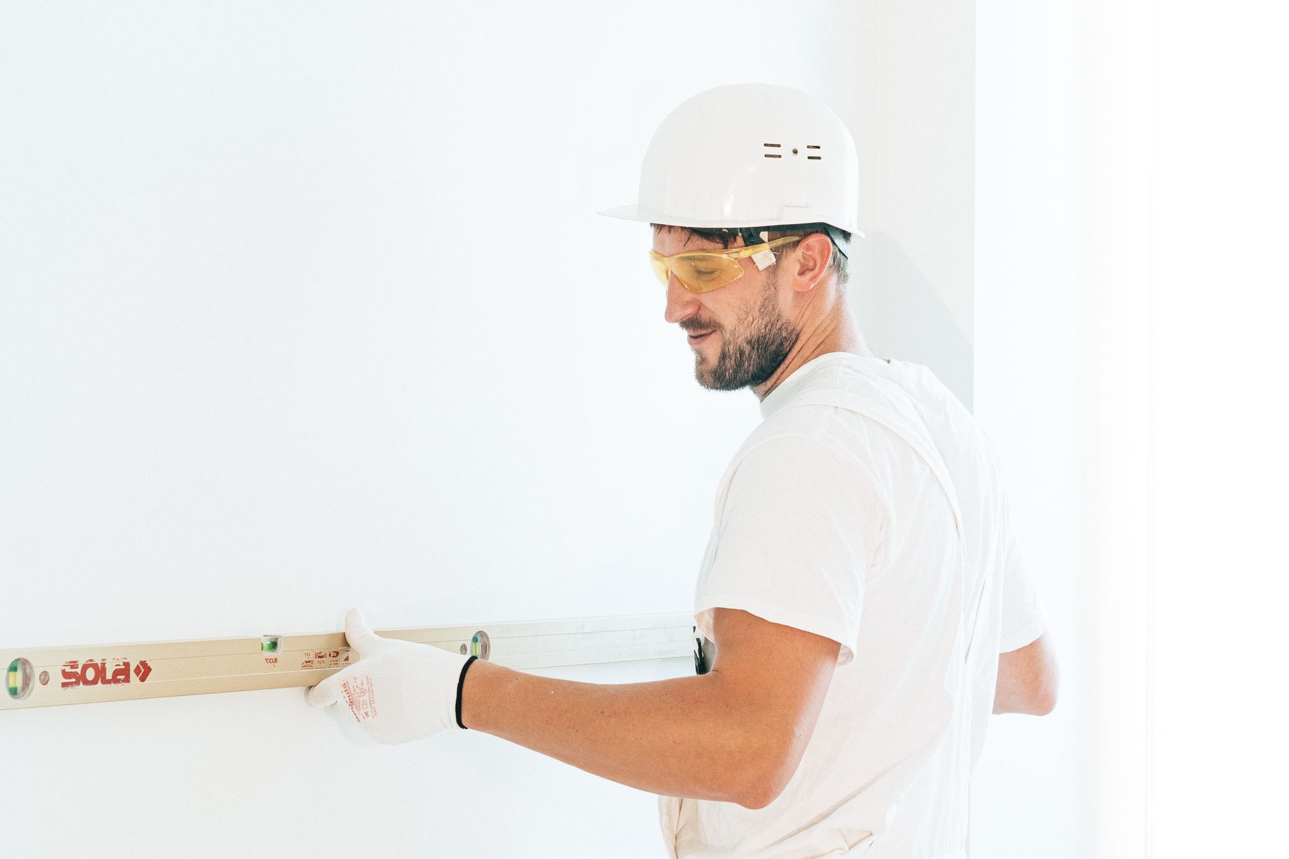 Man wearing safety gear using a spirit level indoors during a construction project